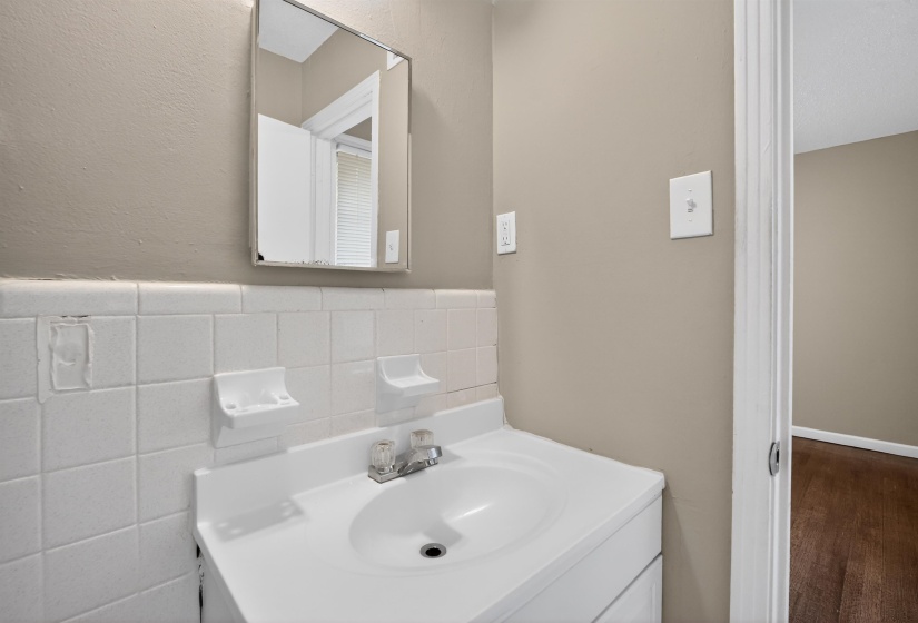 Bathroom vanity with a white integrated sink, chrome faucet, and mirrored cabinet