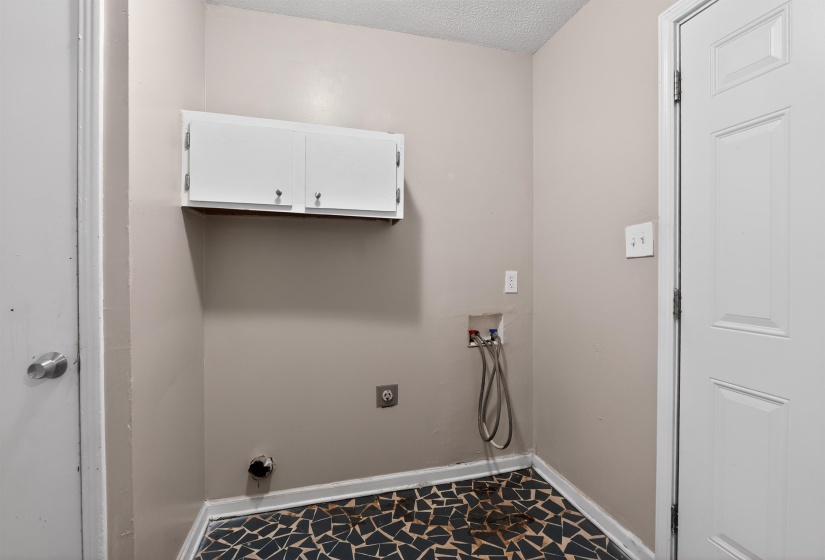 Utility room featuring a patterned floor, light neutral wall paint, and white trim