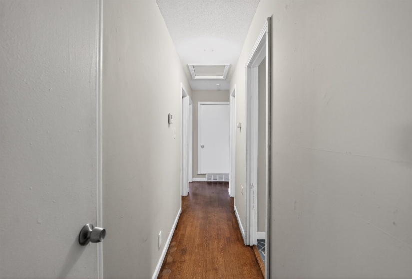 Hallway featuring wood-finish flooring, light-toned walls, white trim, and doors