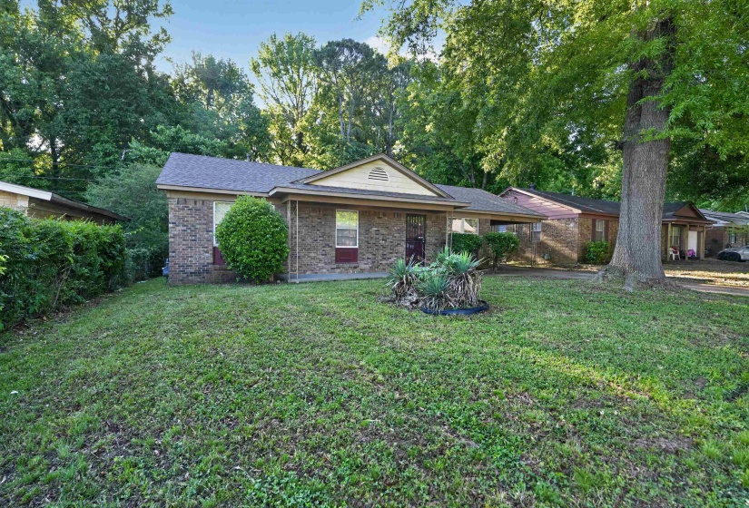 Brick-front home featuring a gabled roofline and an established front yard