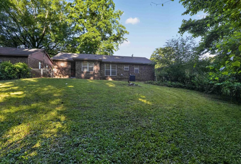 Spacious rear yard with a gentle slope and mature perimeter foliage