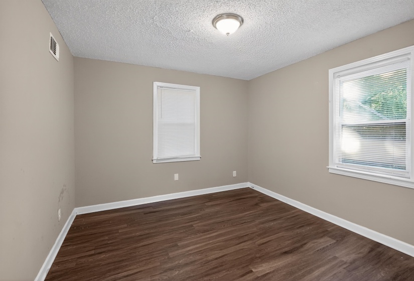 Room featuring wood-finish flooring, two windows with white blinds, neutral wall paint, white baseboards, and a semi-flush ceiling light fixture