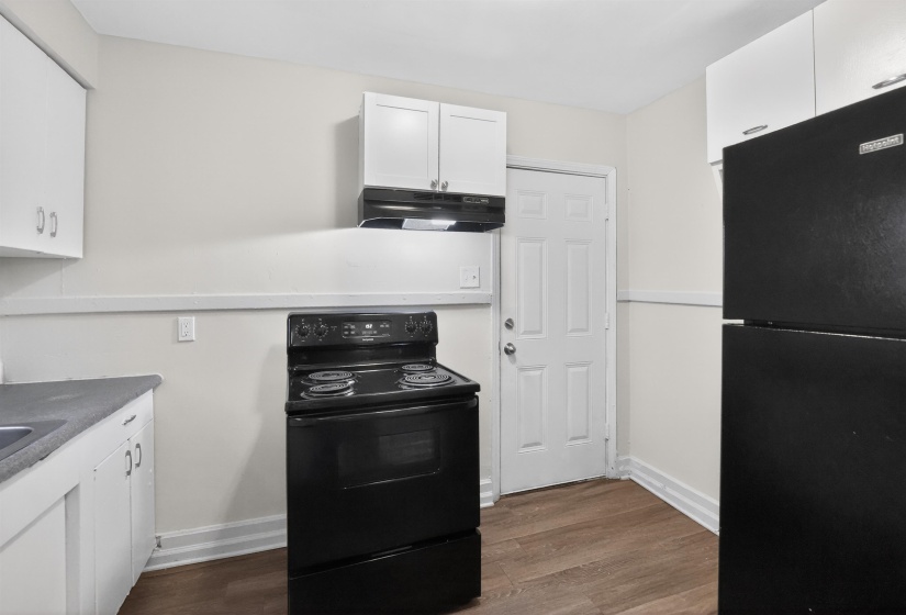 Kitchen featuring white cabinetry, black range, black refrigerator, dark countertop, and wood-finish flooring