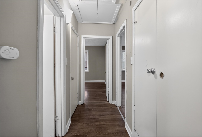 Hallway featuring wood-finish flooring, light gray wall paint, white trim, and multiple doorways