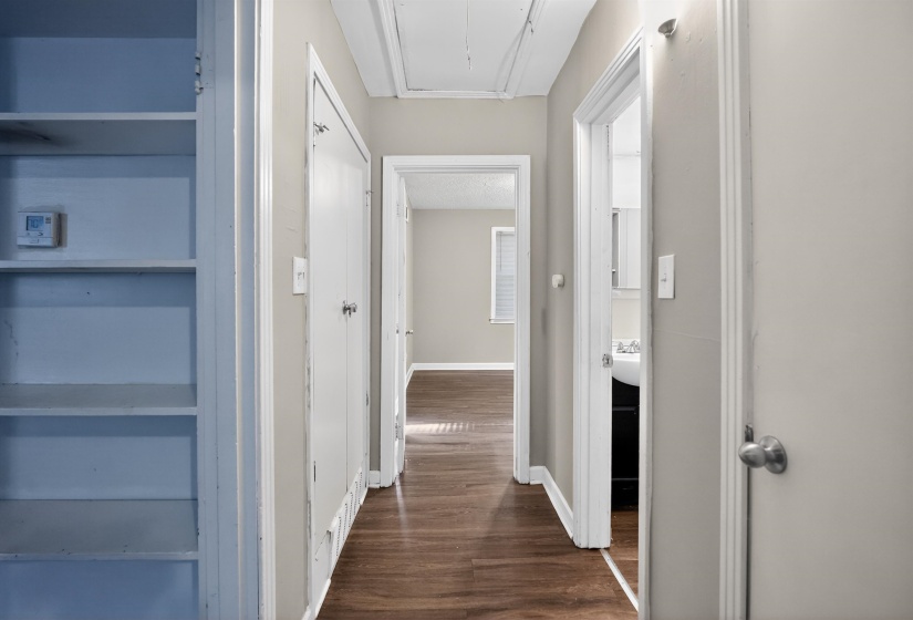 Hallway featuring wood-finish flooring, light neutral wall paint, and white trim