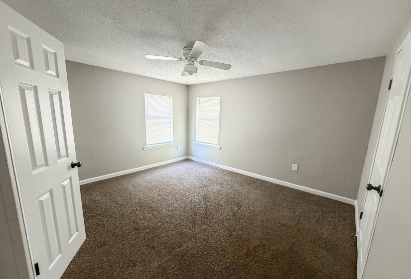 Room featuring neutral-toned walls, brown carpet flooring, and two windows with white blinds