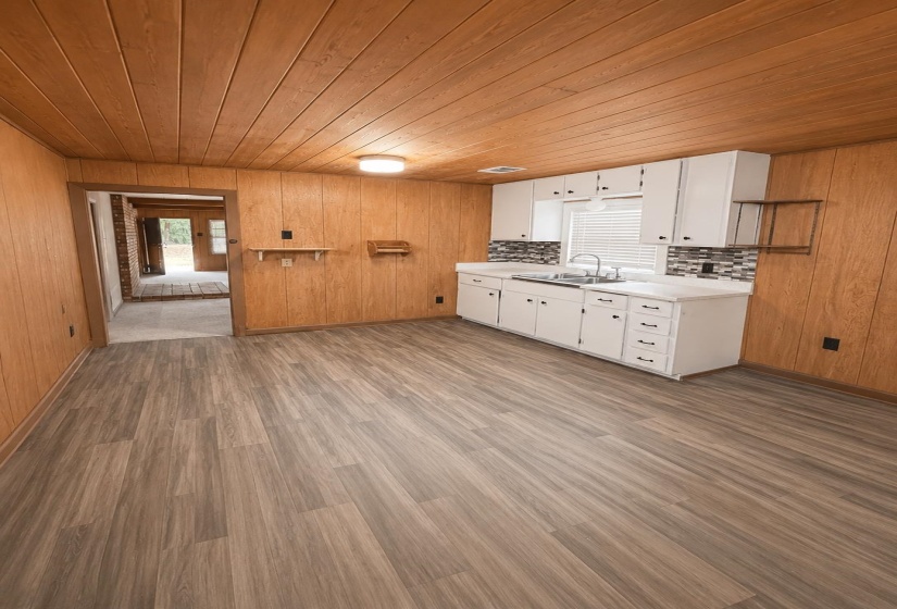 Compact kitchen featuring white cabinetry, a stainless steel sink, and a multi-tone tile backsplash