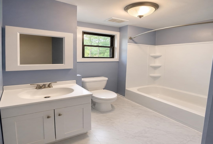Bathroom featuring a white vanity with integrated sink, brushed nickel faucet, and a framed mirror