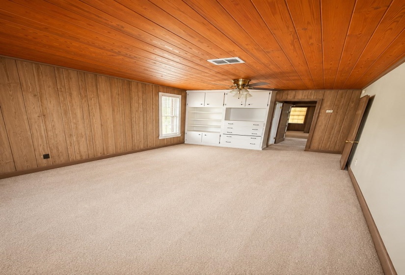 Room featuring wood-finish paneling, a wood-plank ceiling, and neutral-toned carpeting