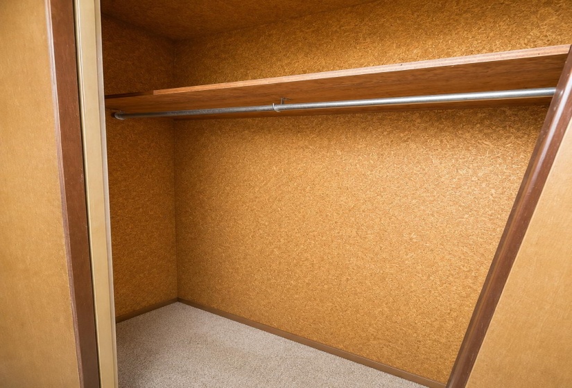 Built-in closet featuring an upper shelf and metal hanging rod