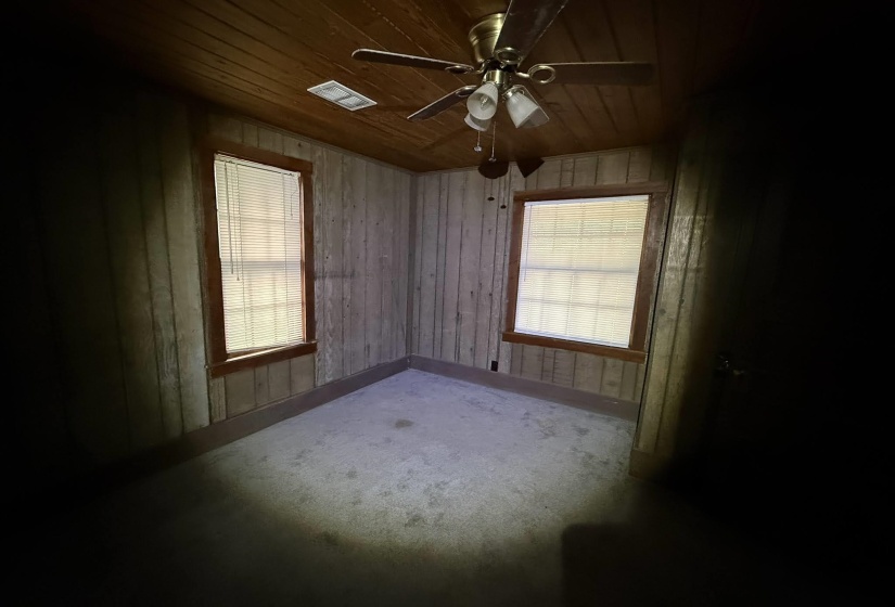 Room featuring wood-finish paneling, a wood-plank ceiling, and two windows with blinds