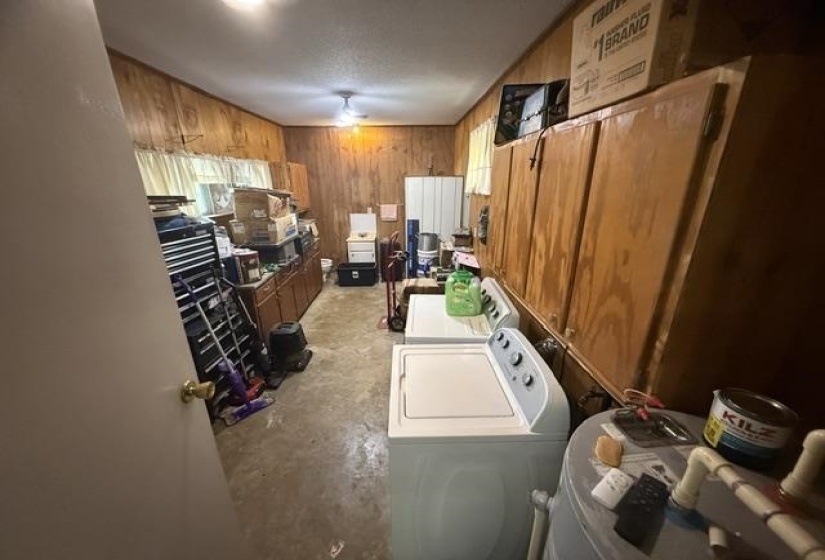 Utility room featuring wood paneling, wood cabinetry, and a concrete floor