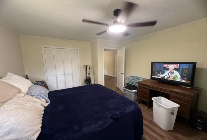 Bedroom featuring wood-finish flooring, a ceiling fan with integrated lighting, and a bi-fold closet door