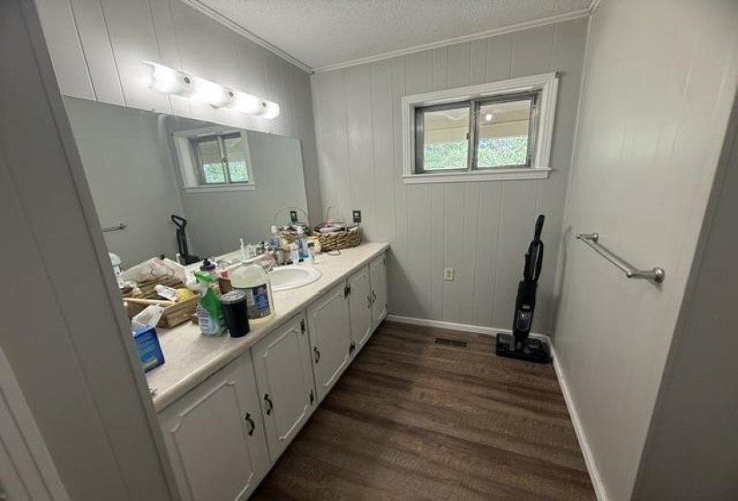Vanity featuring a single-bowl sink, light-toned countertop, and white cabinetry with dark hardware