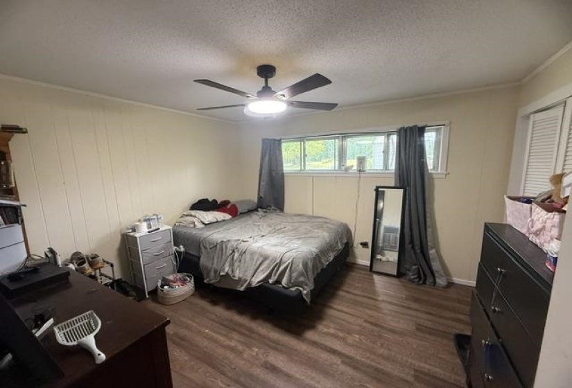 Bedroom featuring wood-finish flooring, white paneling, and an integrated ceiling fan with lighting