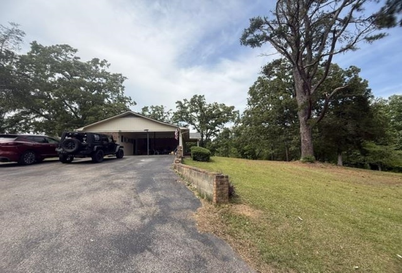 Ranch-style exterior with a covered carport and a sloped, grassy lawn