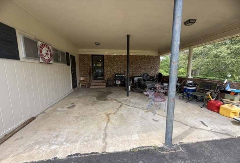 Carport featuring a concrete slab, supporting columns, and a covered ceiling with a flush-mount light fixture