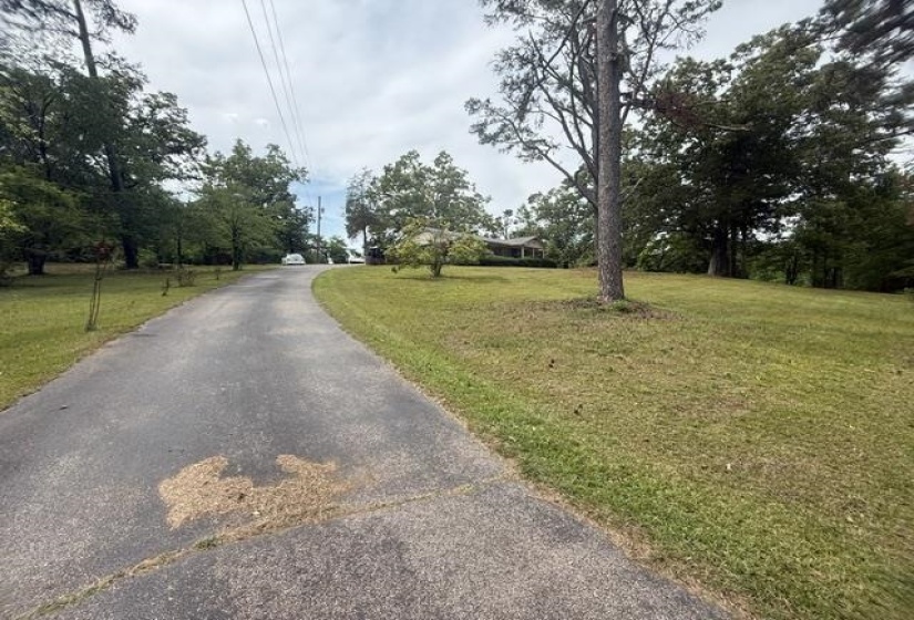 Paved driveway ascending towards a single-story residence with a covered porch