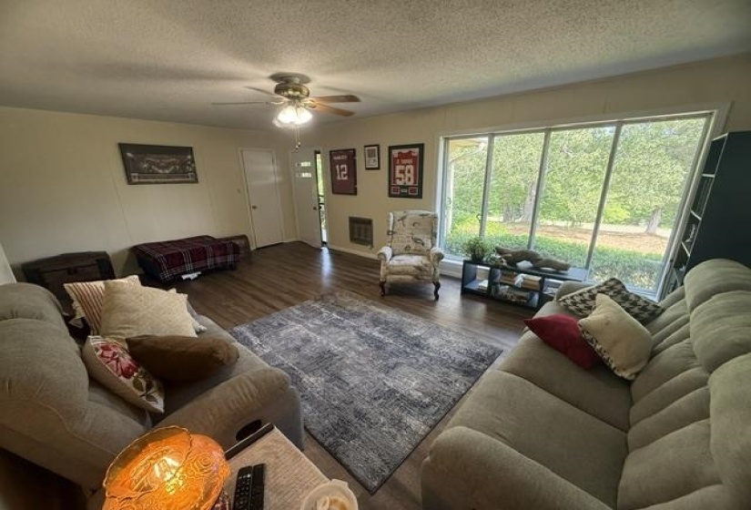 Living area featuring wood-finish flooring, a ceiling fan with light fixture, and a large multi-pane window