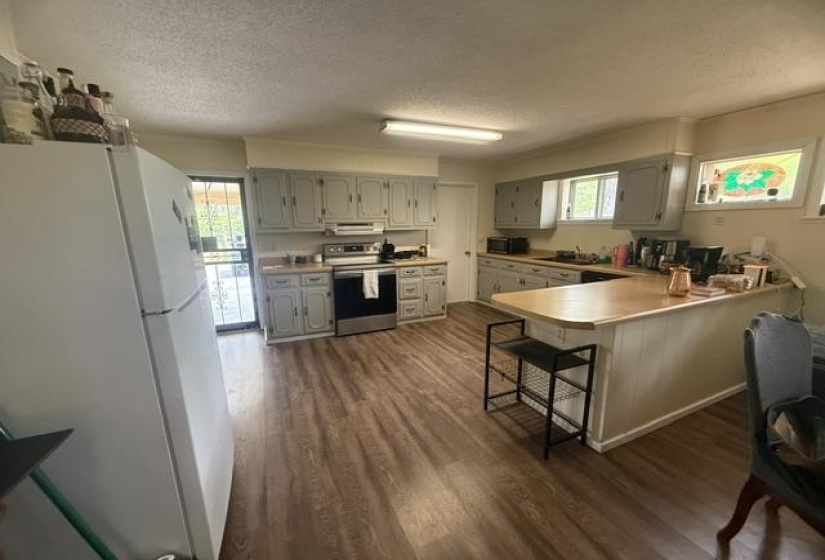Kitchen featuring wood-finish flooring, a breakfast bar, gray cabinetry, and a full suite of stainless steel appliances