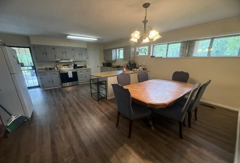 Kitchen and dining area featuring wood-finish flooring, light gray cabinetry, stainless steel range, and a breakfast bar