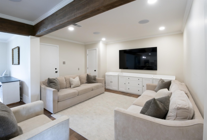 Spacious living area featuring exposed wood-finish beams, recessed lighting, and crown molding