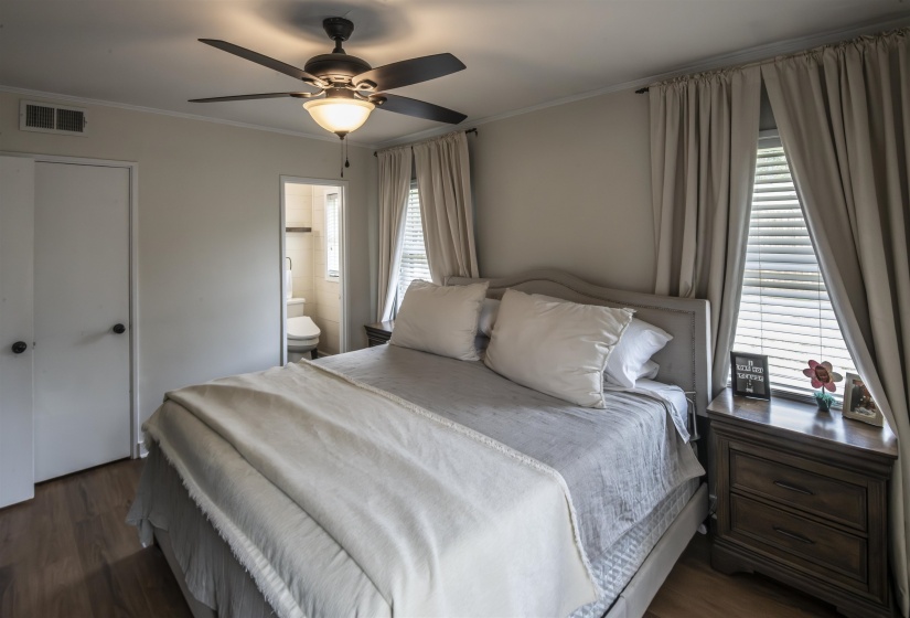Bedroom featuring wood-finish flooring, a ceiling fan with integrated lighting, and a window with blinds and drapery