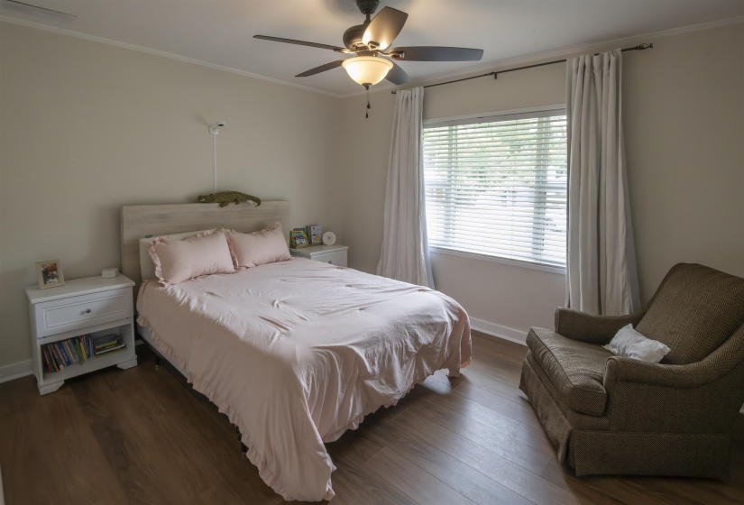 Bedroom featuring wood-finish flooring, a ceiling fan with integrated lighting, and a window with blinds