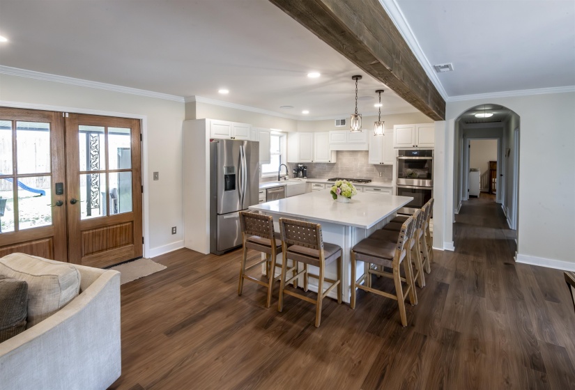 Kitchen featuring a large island with seating, pendant lighting, stainless steel appliances, white cabinetry, and wood-finish flooring