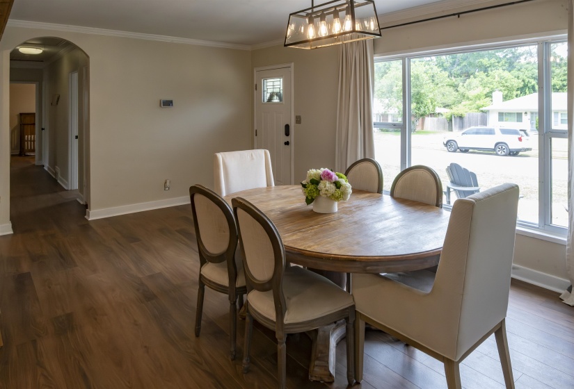 Dining space featuring wood-finish flooring, a large window with drapes, and an overhead rectangular light fixture