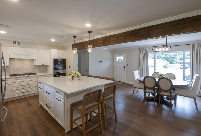 Open-concept kitchen and dining area featuring a prominent wood beam detail