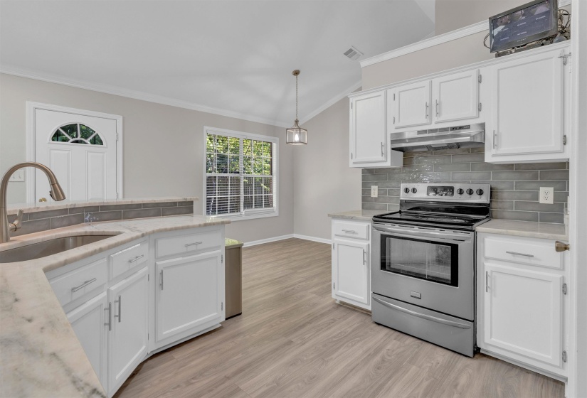 Modern kitchen featuring white cabinetry, light-toned countertops, and a gray subway tile backsplash