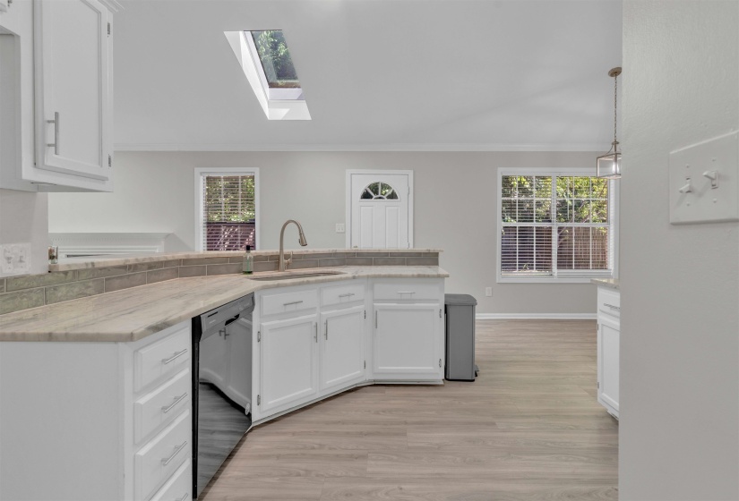 Kitchen featuring white cabinetry, light-toned countertops, a stainless-steel sink with a gooseneck faucet, and a subway tile backsplash