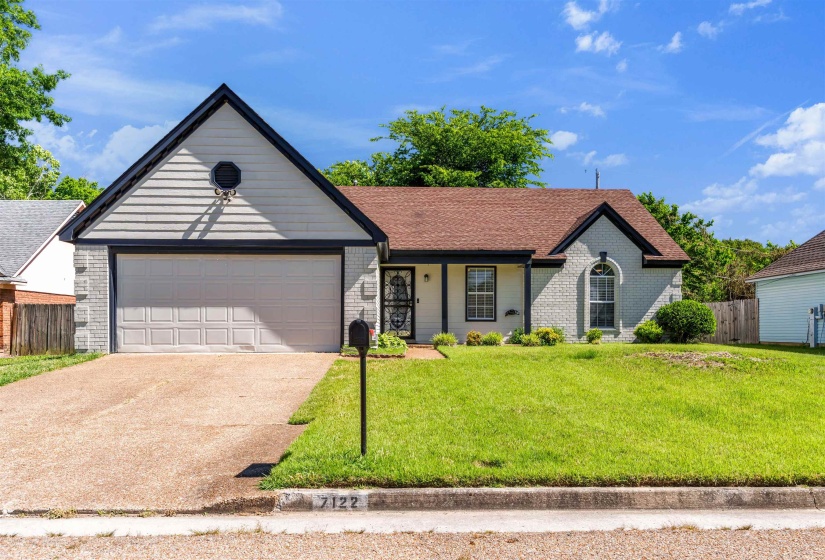 Single-story residence featuring a two-car garage with a paneled door, a prominent front gable with horizontal siding, and a brick facade