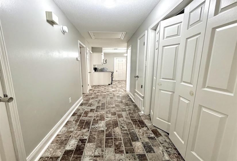 Hallway featuring multi-toned plank flooring, light neutral wall paint, and white trim
