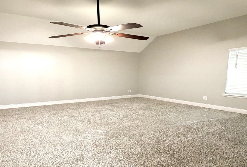 Bedroom featuring vaulted ceilings, neutral-toned carpeting, a ceiling fan with integrated lighting, and a window with blinds