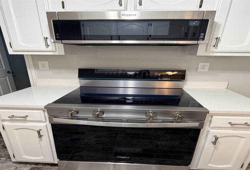 Stainless steel oven range with a black ceramic cooktop, accompanied by a coordinating stainless steel microwave oven