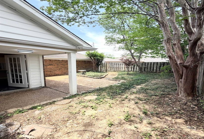 Rear exterior featuring white horizontal siding, a covered patio area with a white support column, and a gravel-finish patio