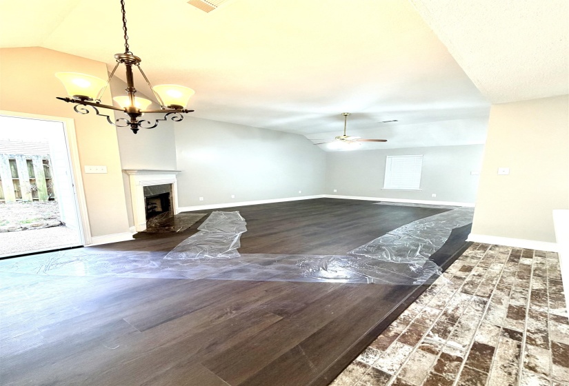 Vaulted ceilings enhance the main living area, featuring wood-finish flooring and a ceiling fan for climate control