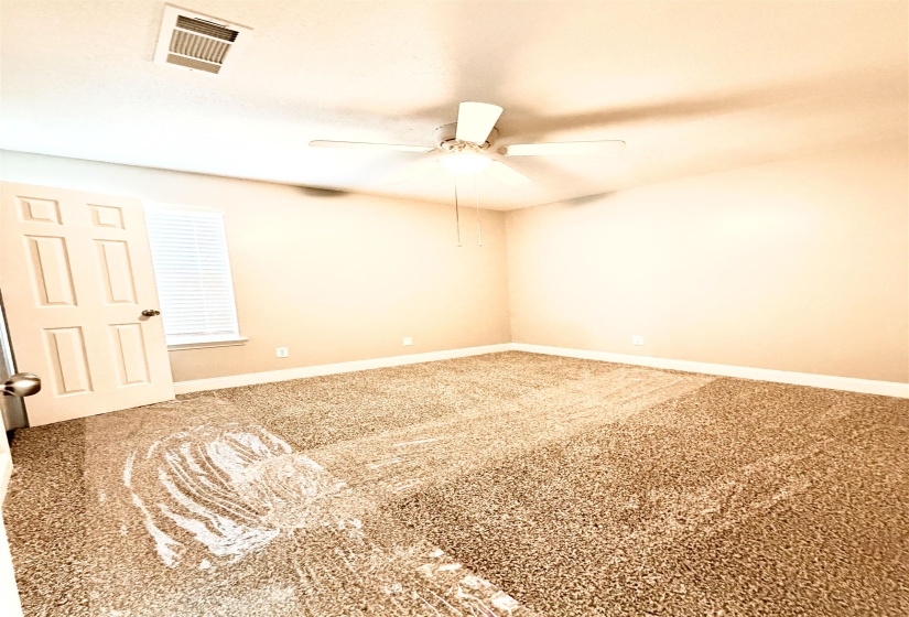 Carpeted room with a ceiling fan, window with blinds, baseboards, and a paneled door