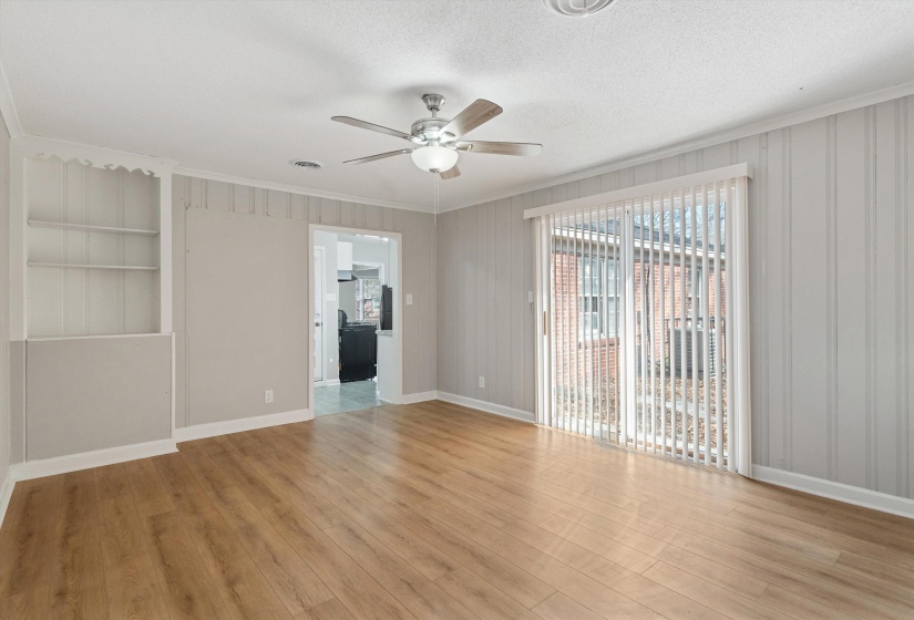Unfurnished room with crown molding, light wood-style flooring, built in features, a textured ceiling, and a ceiling fan