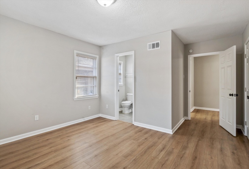 Unfurnished bedroom with light wood finished floors, a textured ceiling, and connected bathroom