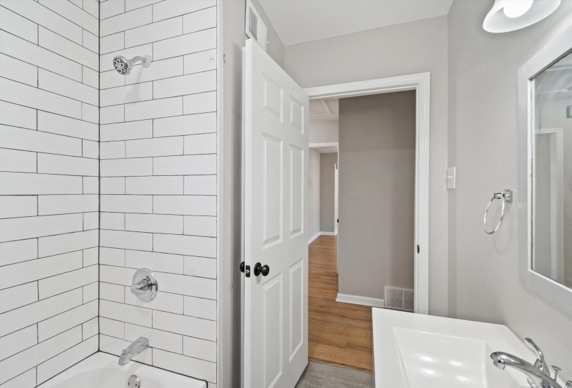 Bathroom with shower / bathtub combination and wood finished floors