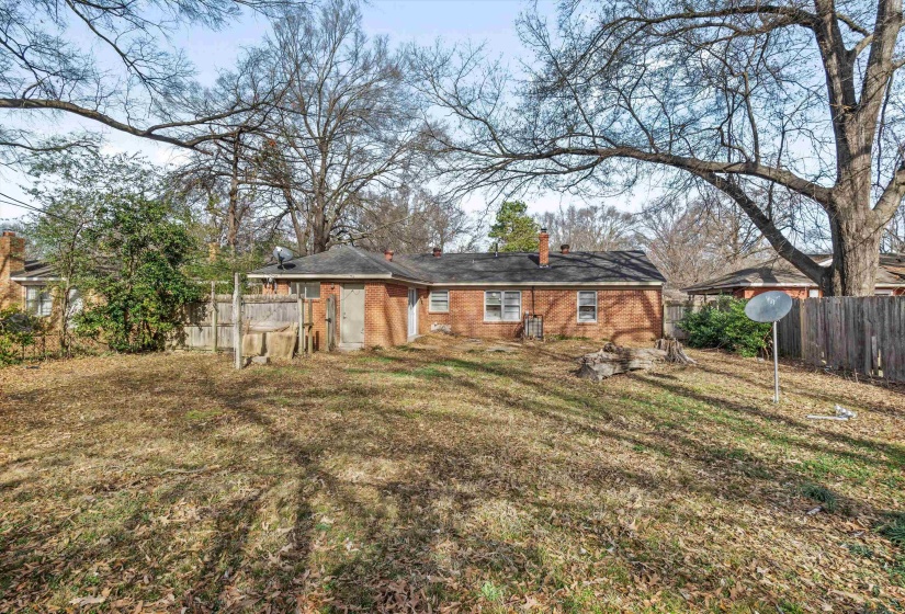 Rear view of property featuring a chimney and brick siding