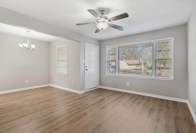 Empty room featuring light wood-style flooring, a ceiling fan, a chandelier, and a textured ceiling
