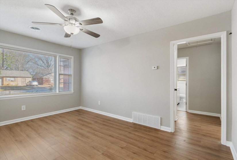 Empty room with attic access, wood finished floors, a ceiling fan, and a textured ceiling