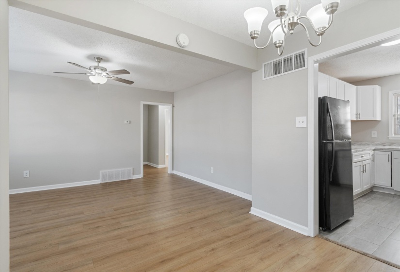 Unfurnished dining area with light wood-style floors, ceiling fan, a chandelier, and a textured ceiling
