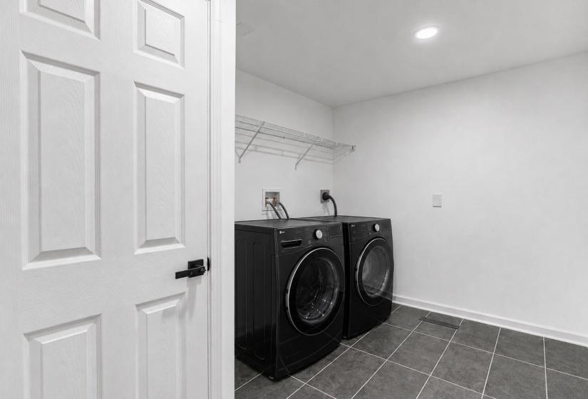 Laundry room featuring dark tile flooring, white walls, recessed ceiling lighting, and wire shelving