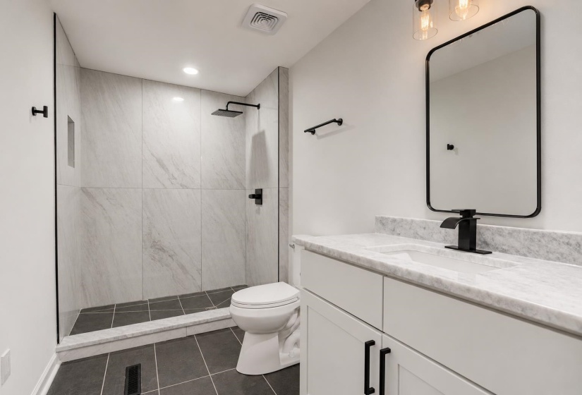 Contemporary bathroom featuring a walk-in shower with light-toned wall tile, a frameless glass enclosure, and a matte black rainfall showerhead