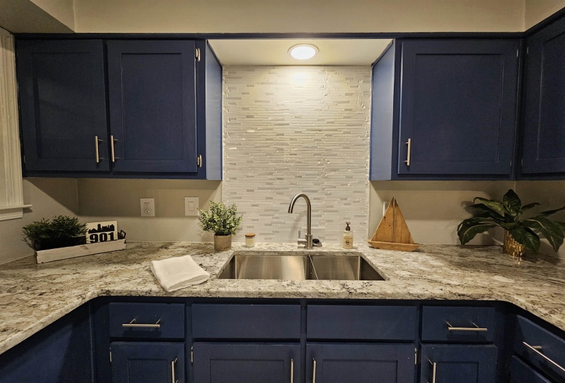 Kitchen featuring light stone counters, tasteful backsplash, and blue cabinetry